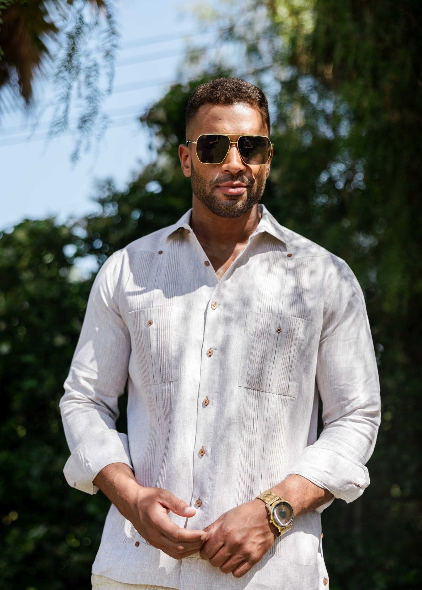 A man wears an off-white long-sleeve Men’s 100% Linen Guayabera Shirt with heritage pleats.