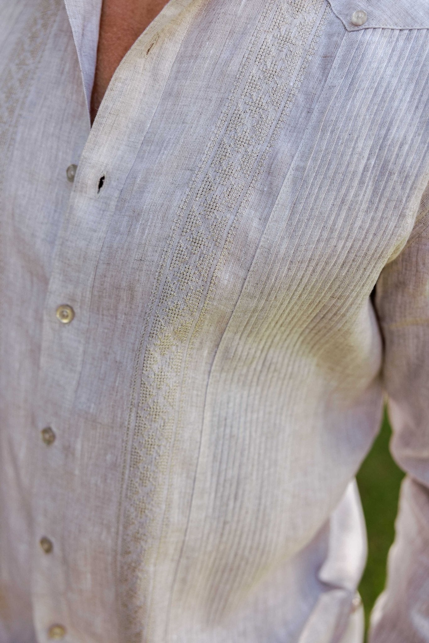 Close-up of a beige linen long sleeve Guayabera shirt with contrast panel detailing, buttoned.