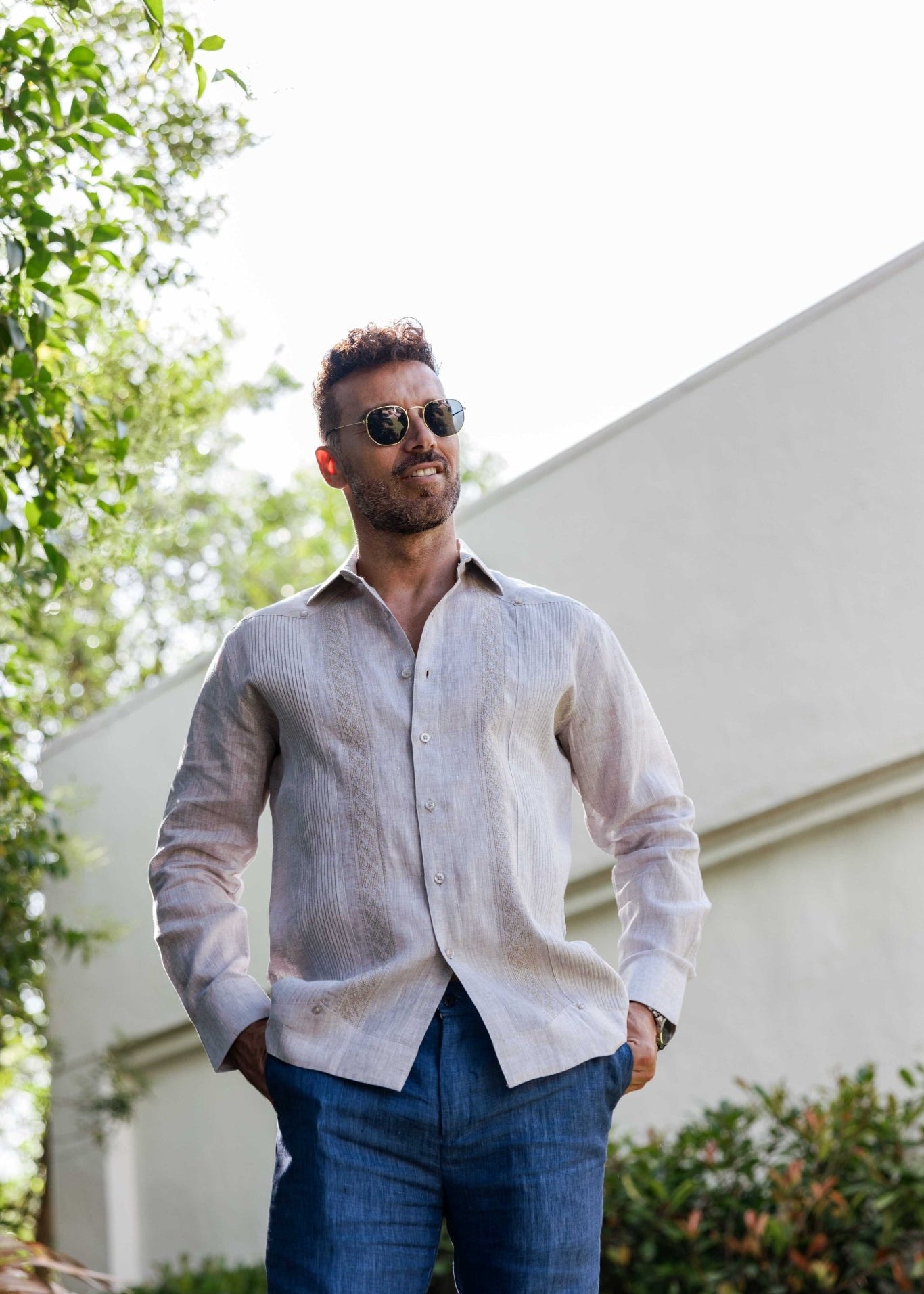 Man wearing the light beige 100% Linen Contrast Panel Guayabera Shirt, long sleeve, looking up to the right.
