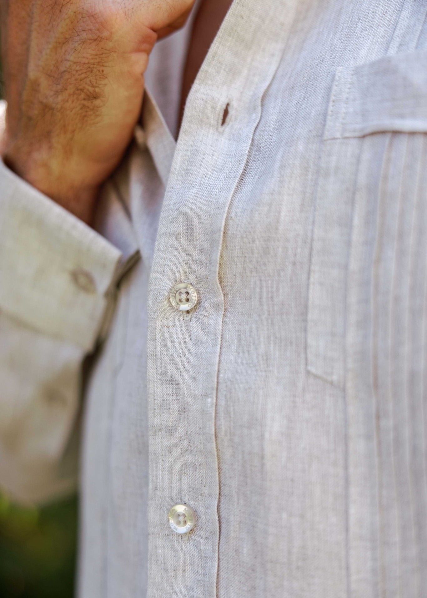 Macro shot of beige 100% linen fabric showing the buttons and vertical tonal pleat construction.