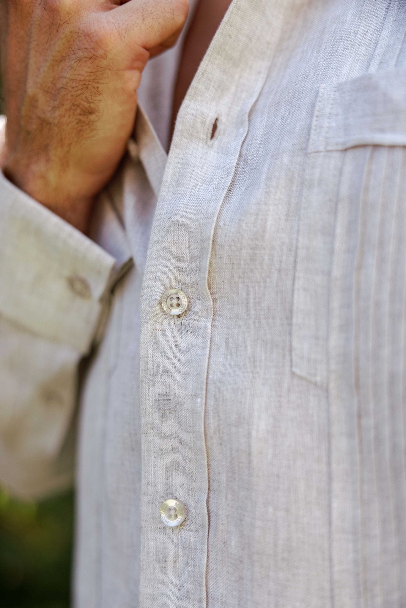 Macro shot of beige 100% linen fabric showing the buttons and vertical tonal pleat construction.