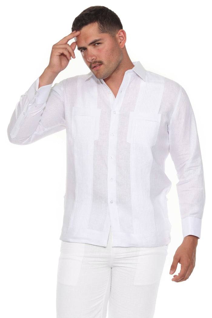 A man wearing a beige long sleeve linen guayabera with white trousers standing outdoors.