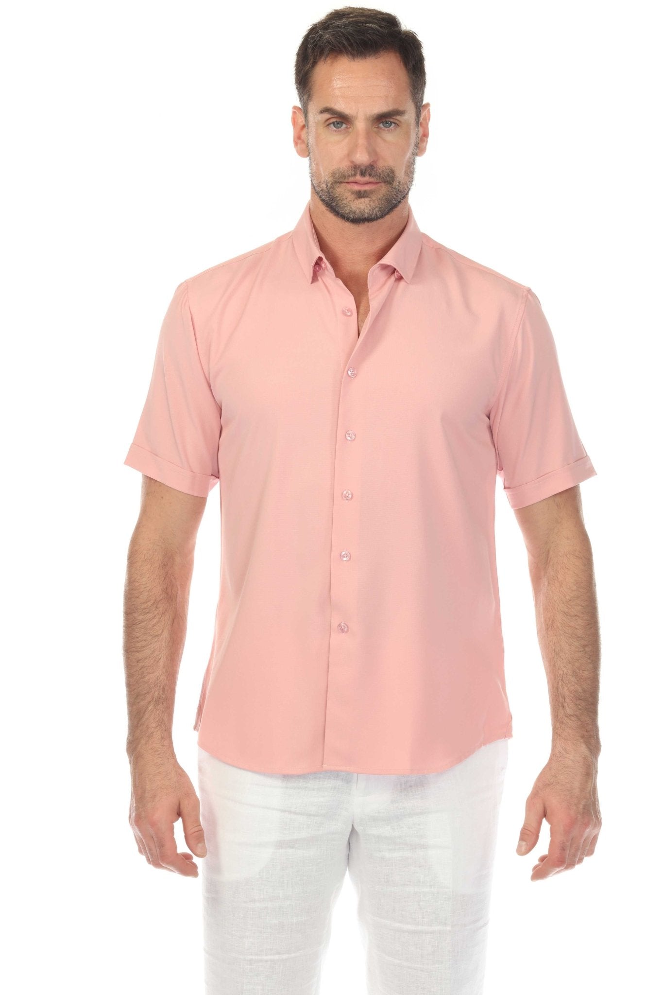 A man wears a light pink Menâ€™s Classic 4-Way Stretch Short Sleeve Shirt with white pants, facing forward.