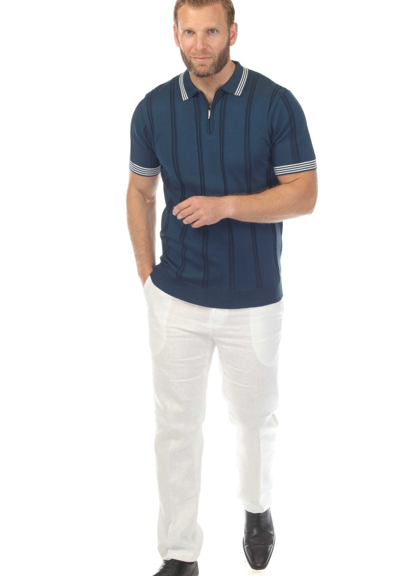 A man wearing a navy Men's Premium Knit Textured Polo Shirt with Stripe Accents and white pants.