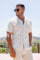 A person wears a tan Striped Linen Blend Resort Shirt and matching pants, standing outdoors in sunlight.