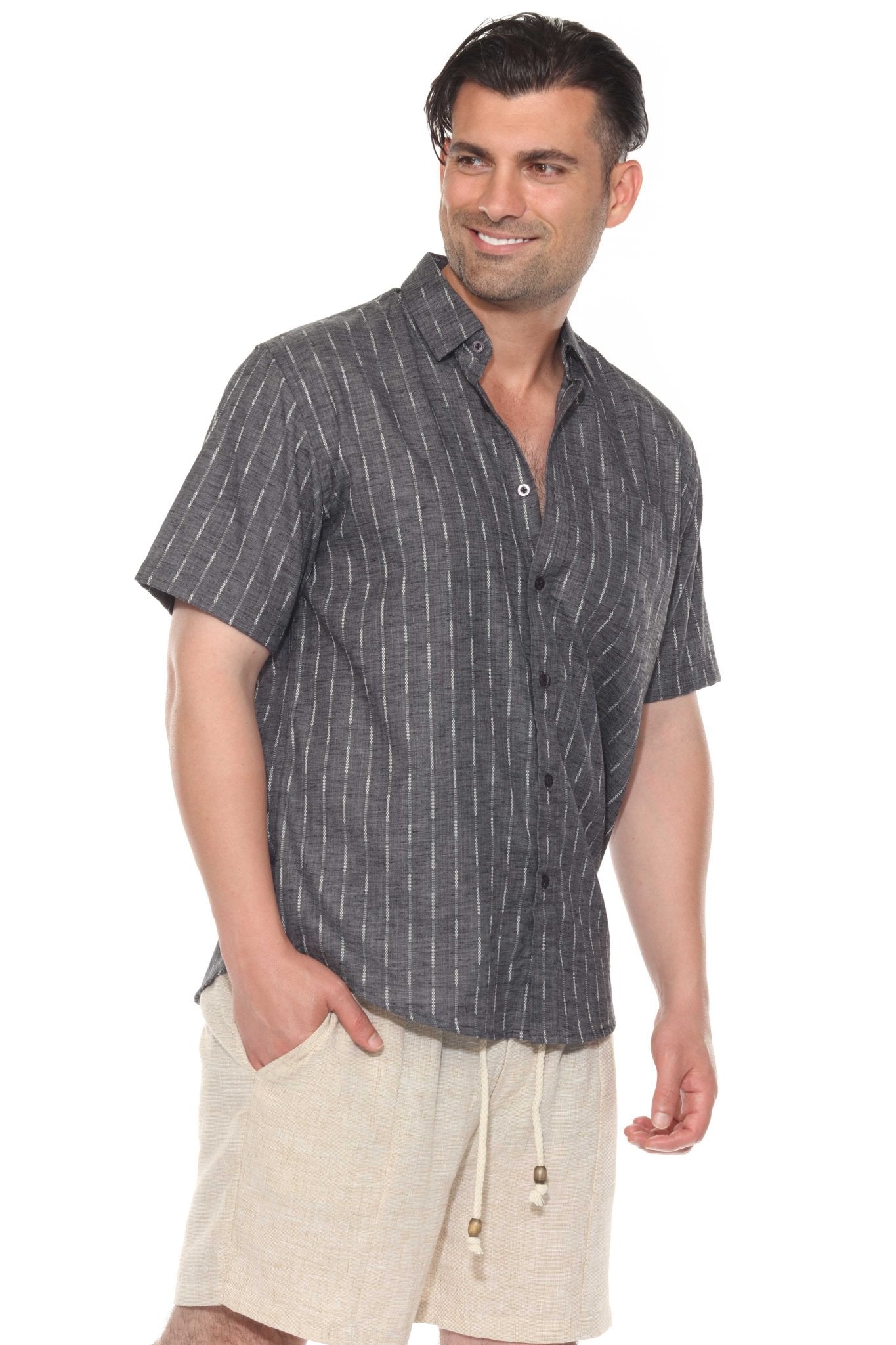Man in a grey Men’s Pinstripe Resort Shirt, short sleeves, with an open collar standing with his hand in his beige shorts pocket.