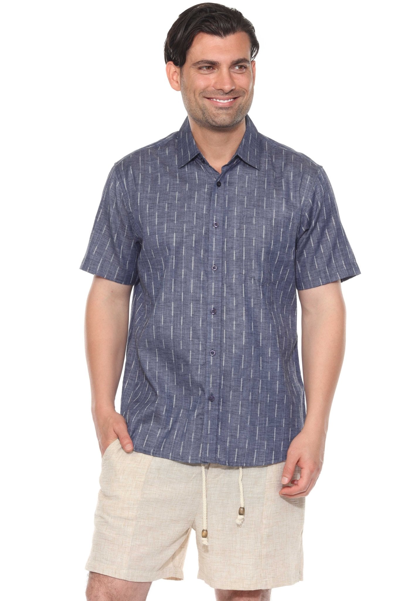 A man smiles wearing the blue Men’s Pinstripe Resort Shirt buttoned up, with light shorts.