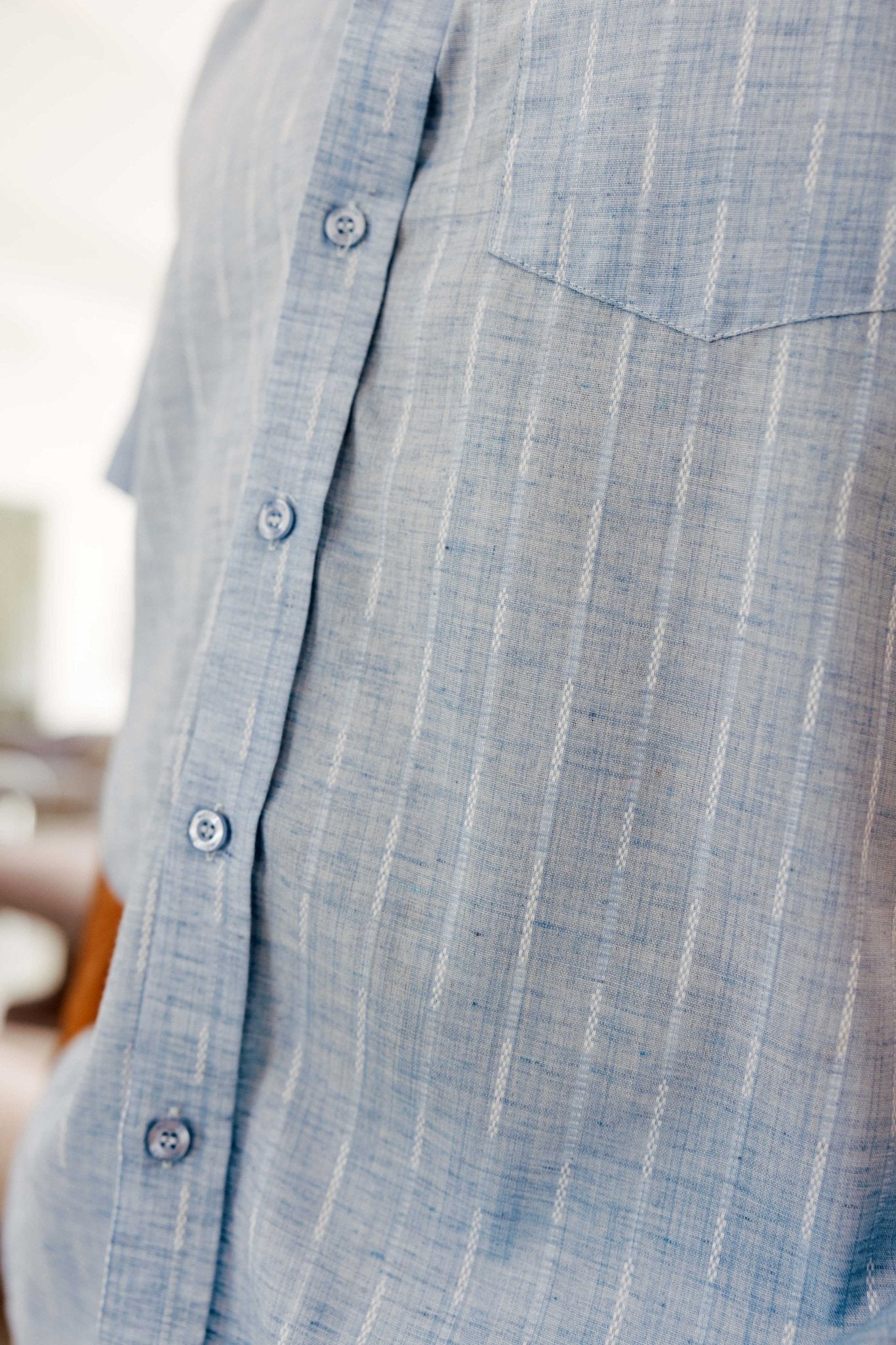 Close-up of the light blue Men’s Pinstripe Resort Shirt, showing the short sleeves, front buttons, and chest pocket.