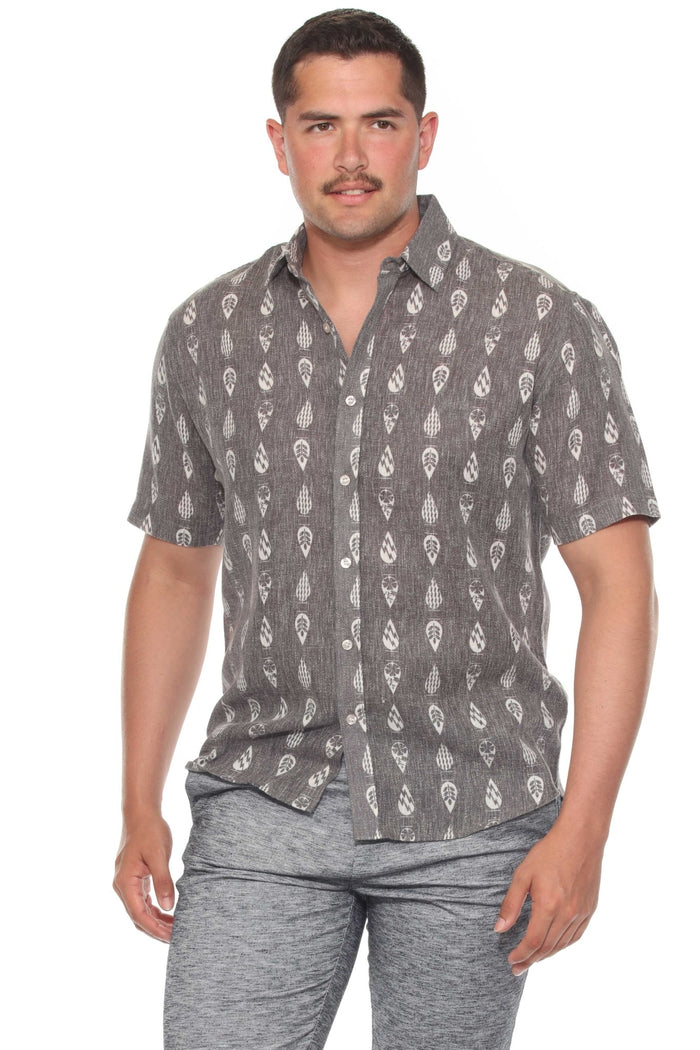 Man wears the gray resort print men's short sleeve button-up shirt outdoors, sunglasses on, looking off to the side.