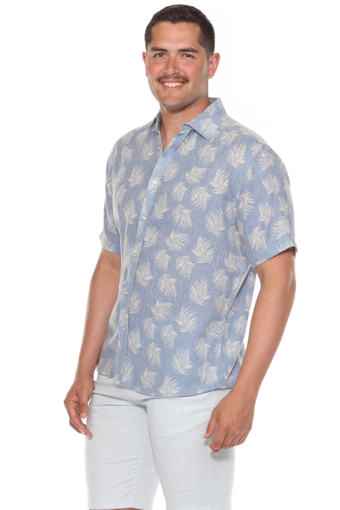 Man wears the gray resort print men's short sleeve button-up shirt outdoors, sunglasses on, looking off to the side.