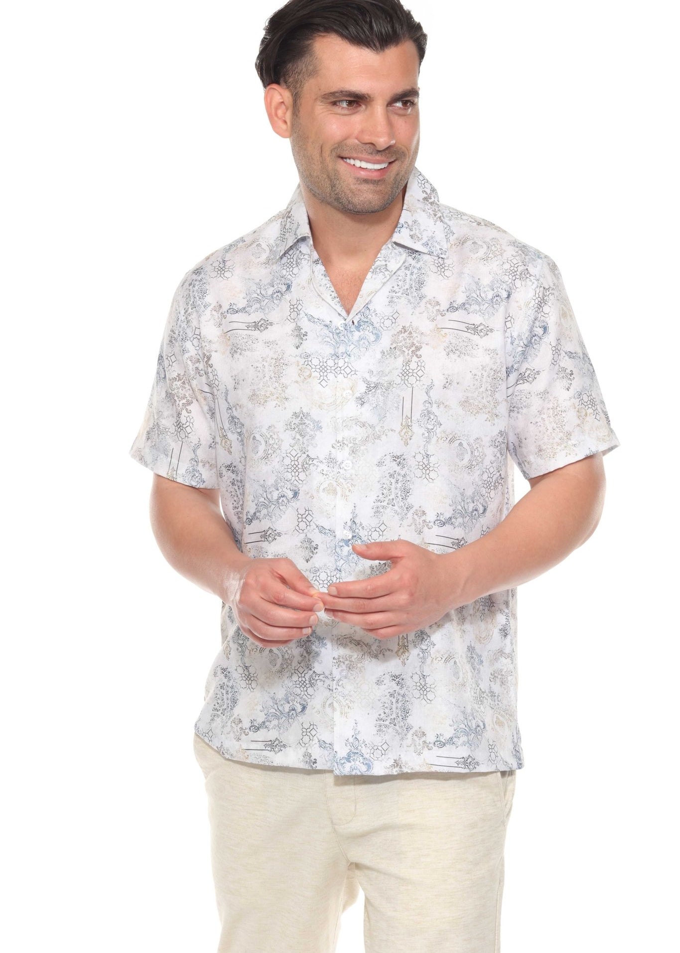 A man smiles wearing a pale tropical print Men’s Resort Shirt and tan pants.