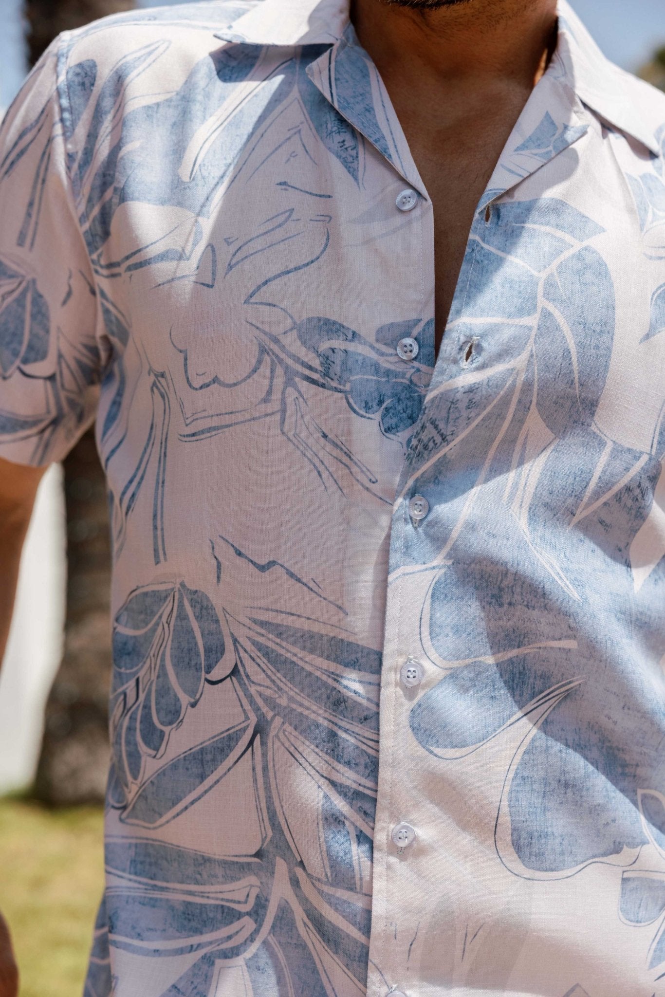 Close-up of a Men's Tropical Print Resort Shirt, with a blue floral design and white buttons.