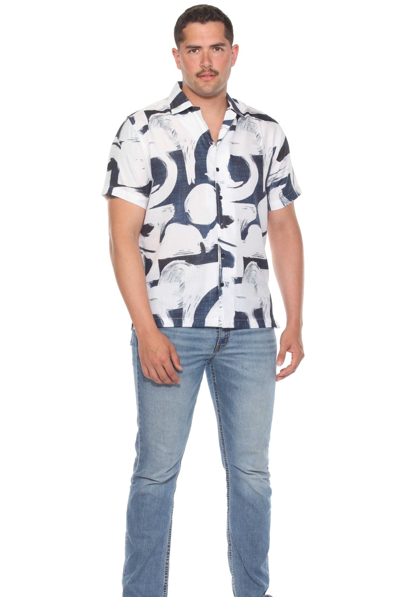 A man in a white Men’s Tropical Print Resort Shirt with a navy pattern and wearing denim jeans stands facing forward.