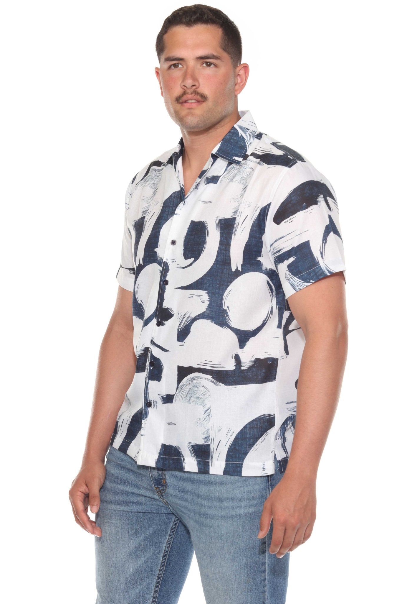 A man wears the Men’s Tropical Print Resort Shirt; it is white with a stylized dark blue tropical print.