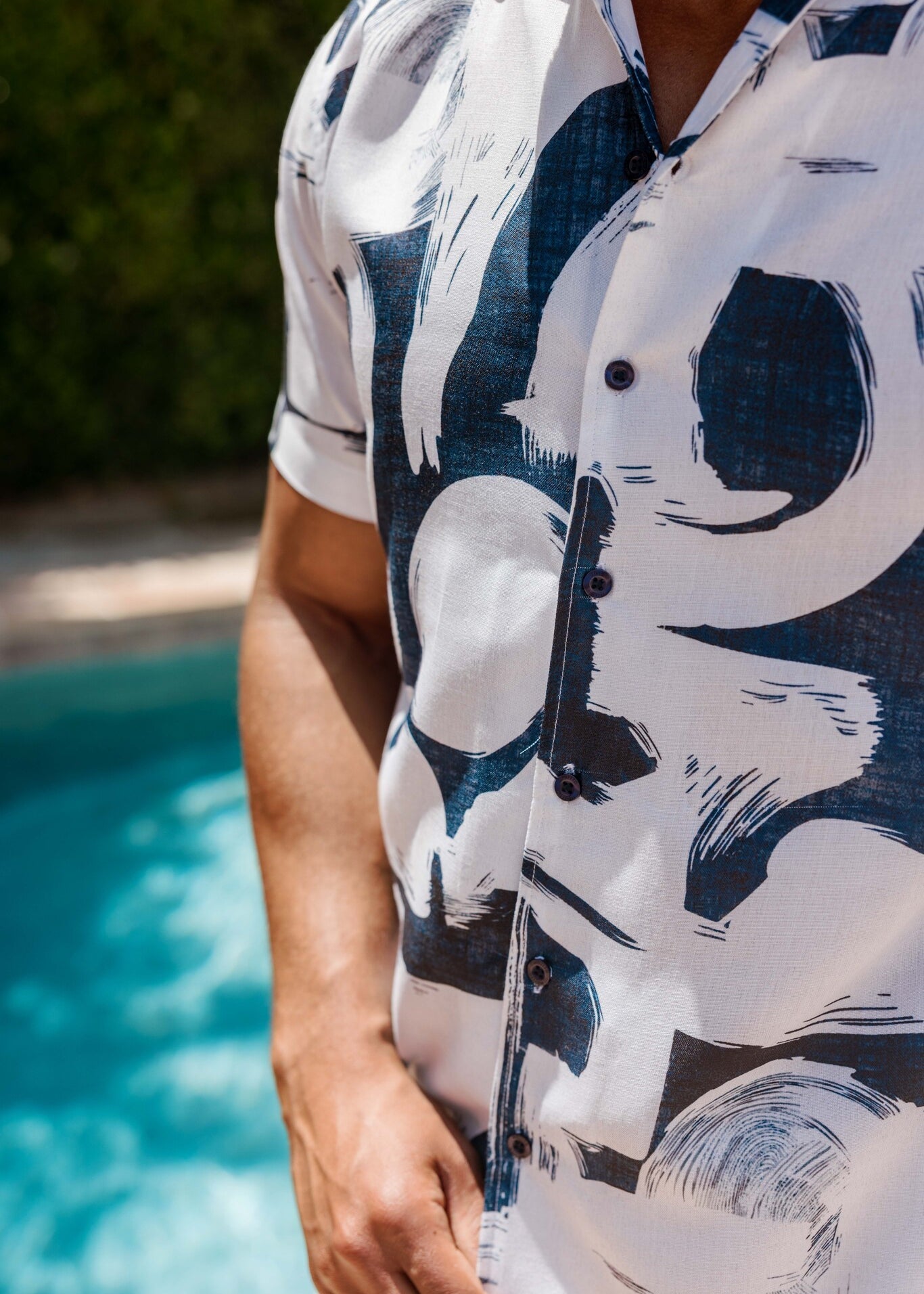 Close-up of a man in a white Men’s Tropical Print Resort Shirt with abstract navy blue print and dark button detail.