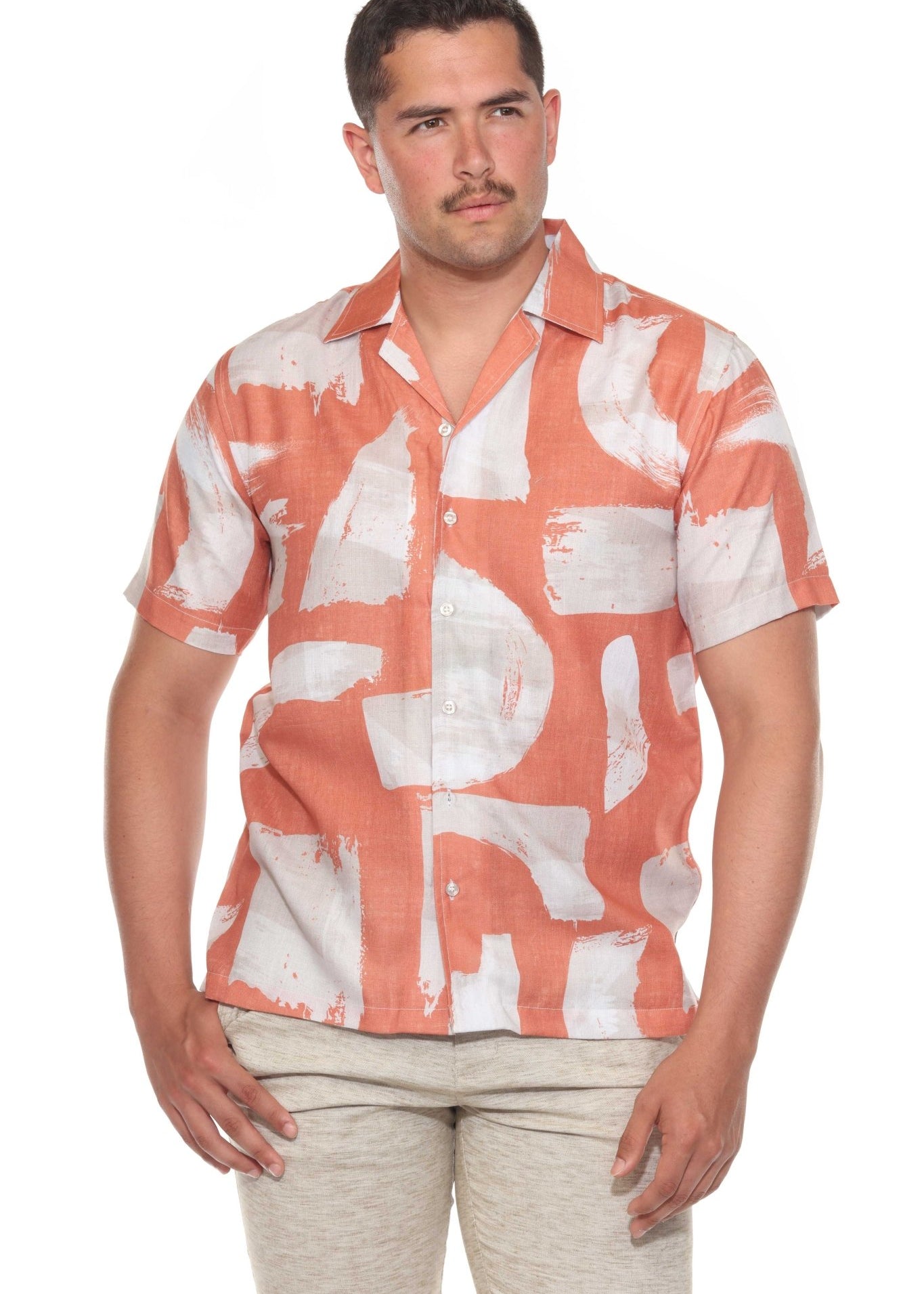 Front view of a man wearing an apricot and white Men’s Tropical Print Resort Shirt, buttoned halfway.