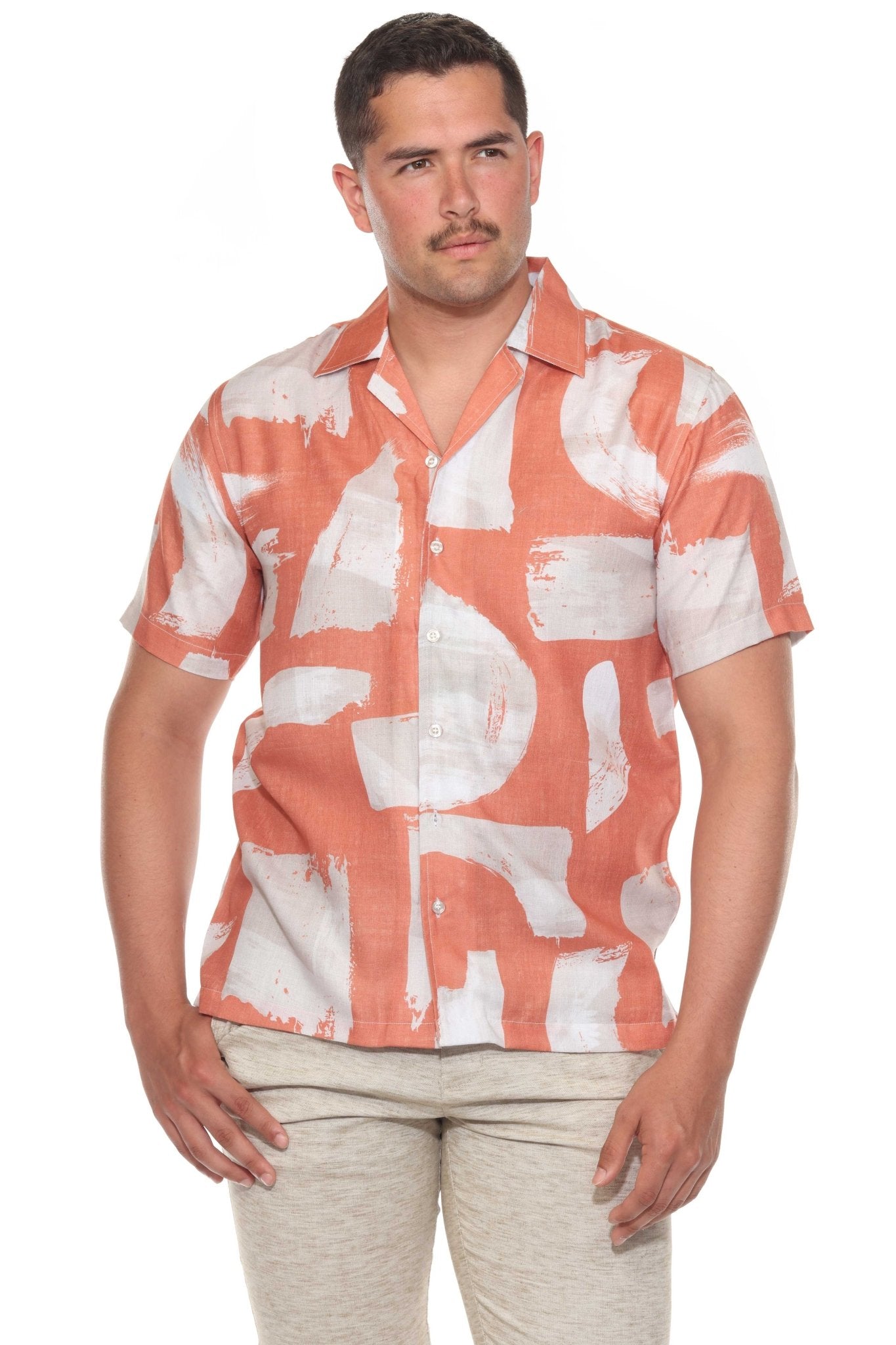 Front view of a man wearing an apricot and white Men’s Tropical Print Resort Shirt, buttoned halfway.