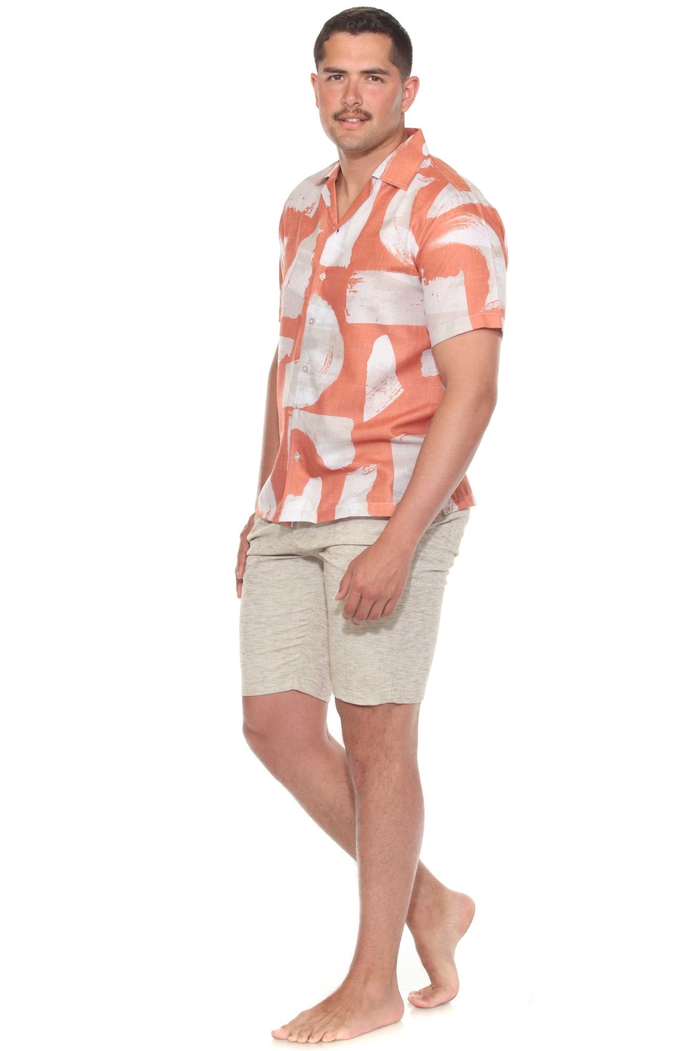 A man models the Men’s Tropical Print Resort Shirt with an orange and white pattern, paired with khaki shorts.