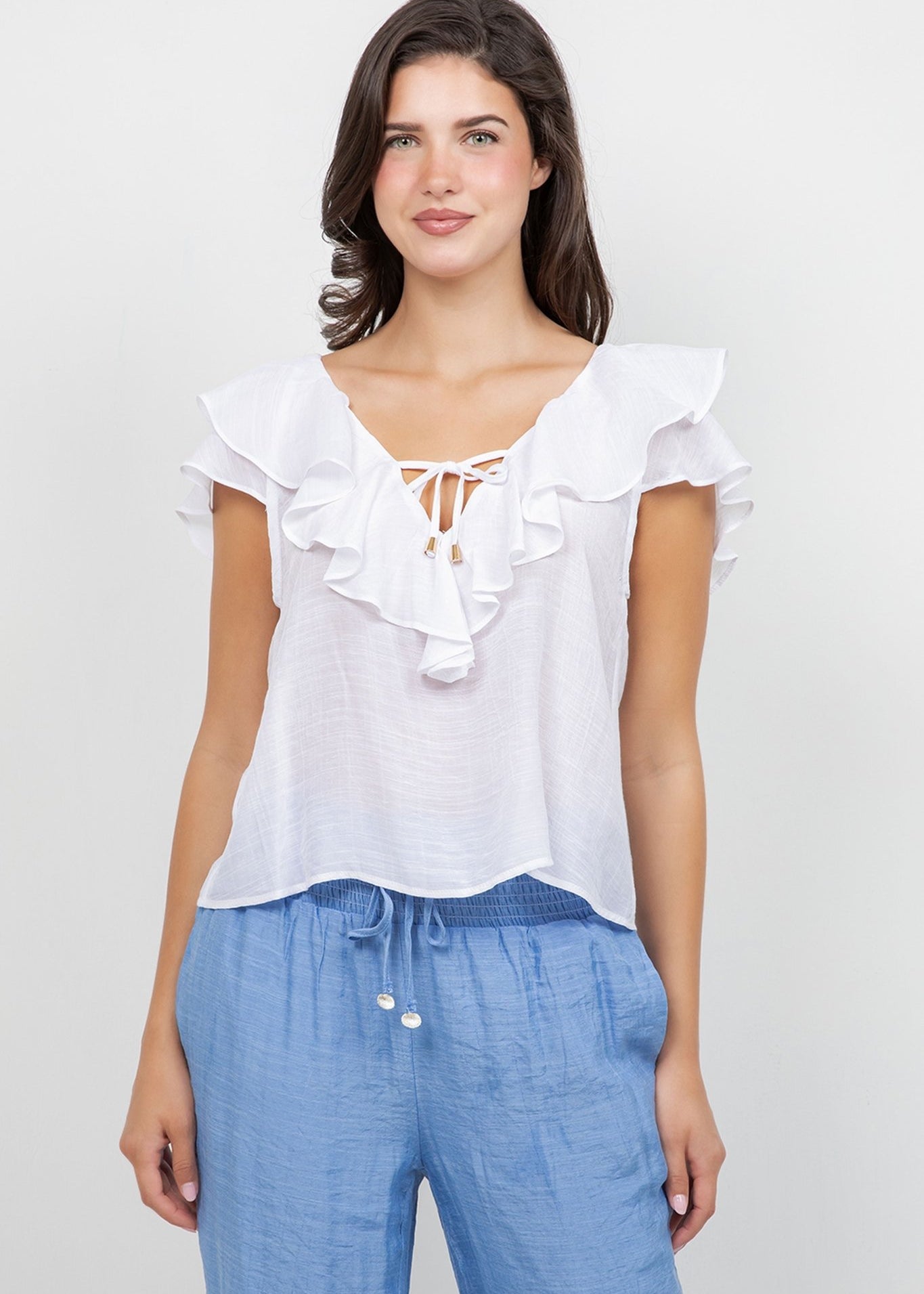 Model wearing a white Ladies Casual Boho Ruffled Tie Blouse with blue pants, facing forward.