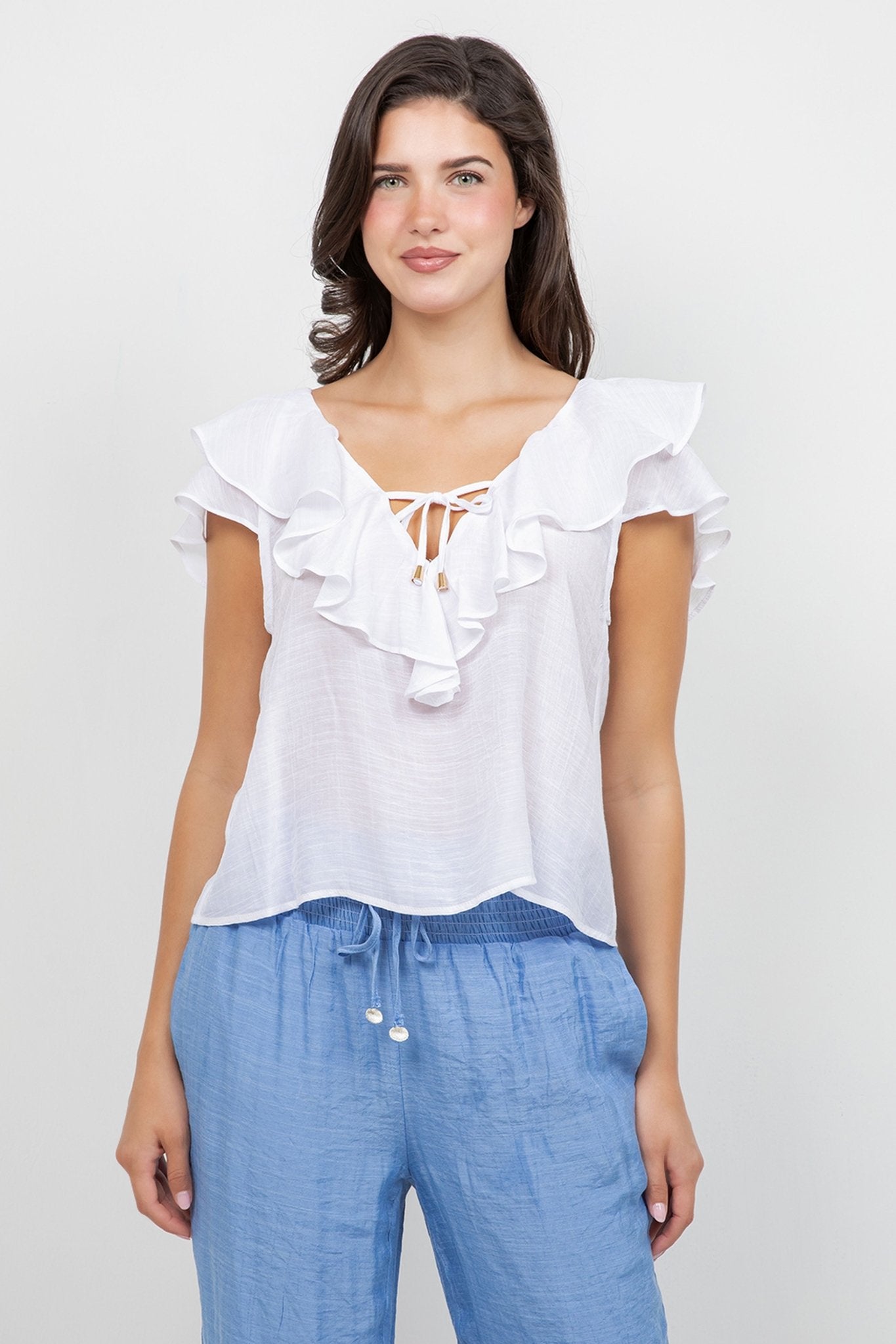 Model wearing a white Ladies Casual Boho Ruffled Tie Blouse with blue pants, facing forward.