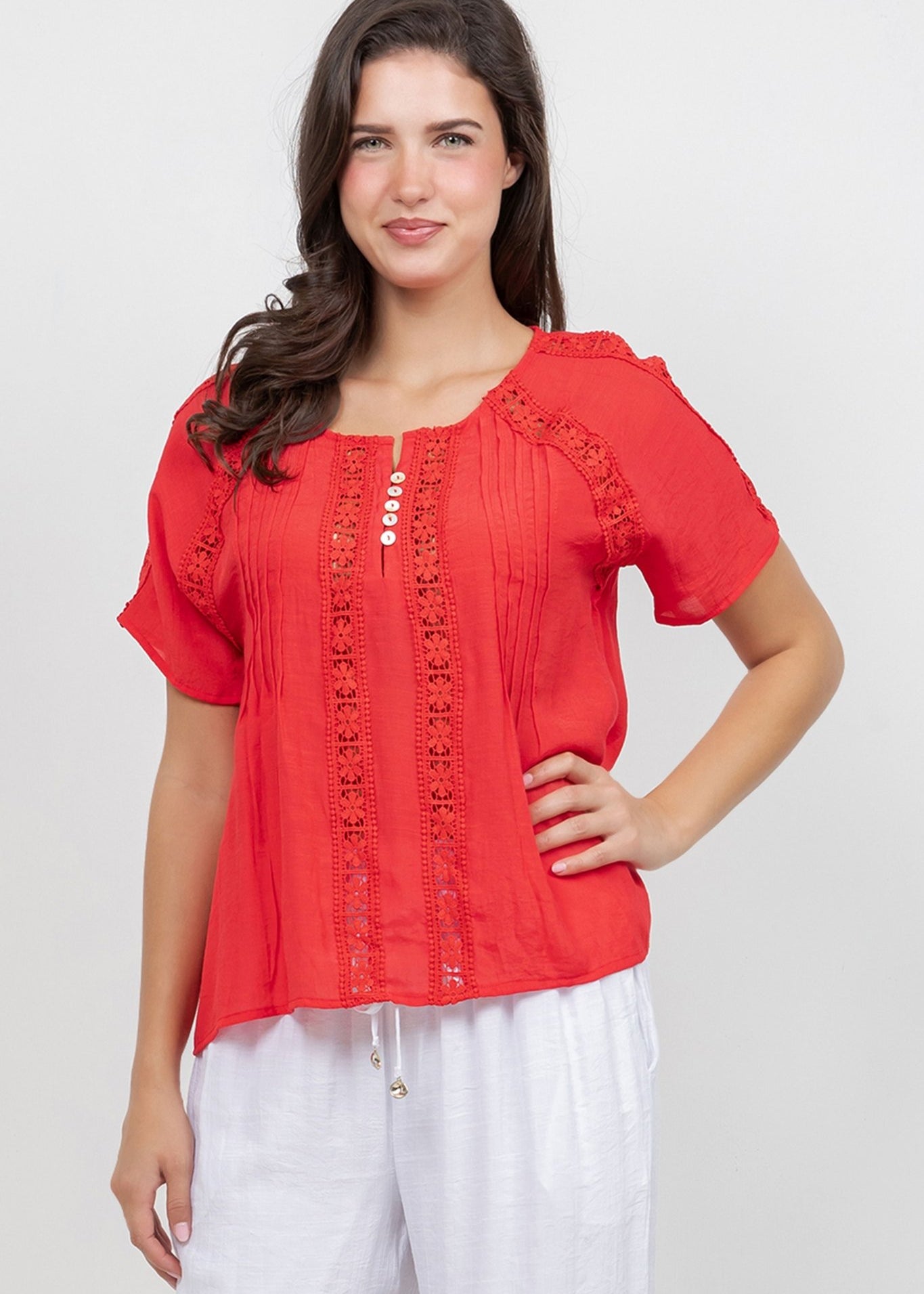 A woman wearing a red Ladies Boho Pleated Lace Panel Blouse with lace details.