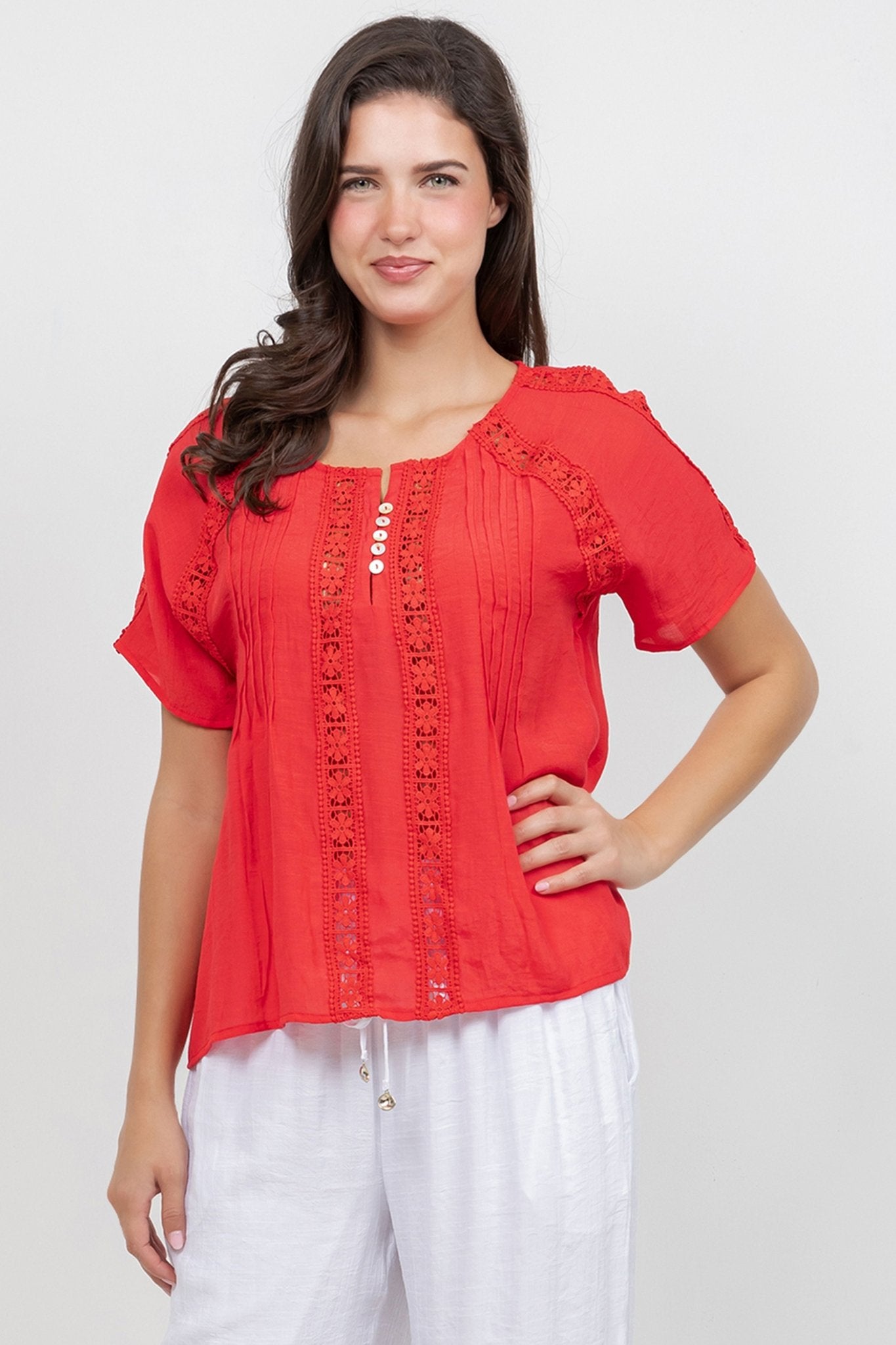 A woman wearing a red Ladies Boho Pleated Lace Panel Blouse with lace details.