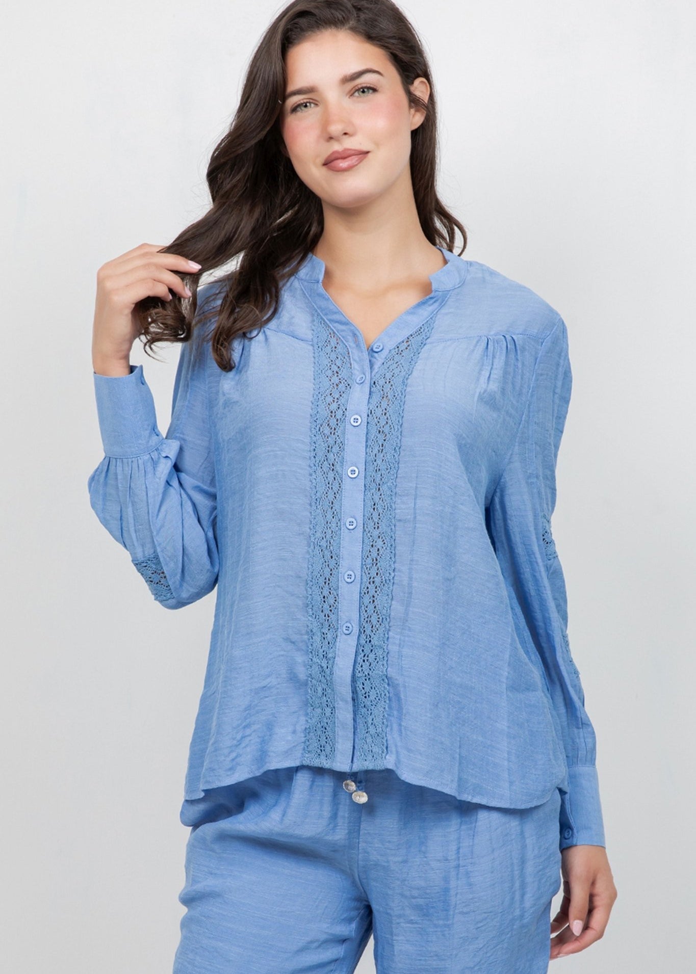 Woman models the light blue Ladies Boho Lace Panel Pleated Long Sleeve Blouse and matching pants.