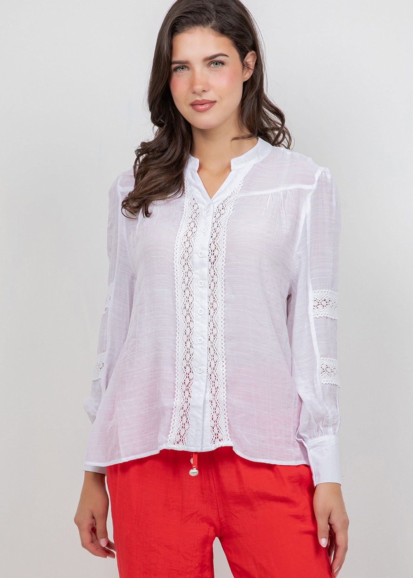 Front view of a woman wearing a white Ladies Boho Lace Panel Pleated Long Sleeve Blouse with lace detail.