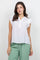 A woman wears a white Ladies Boho Flutter Sleeve Button Blouse and green pants, front view.
