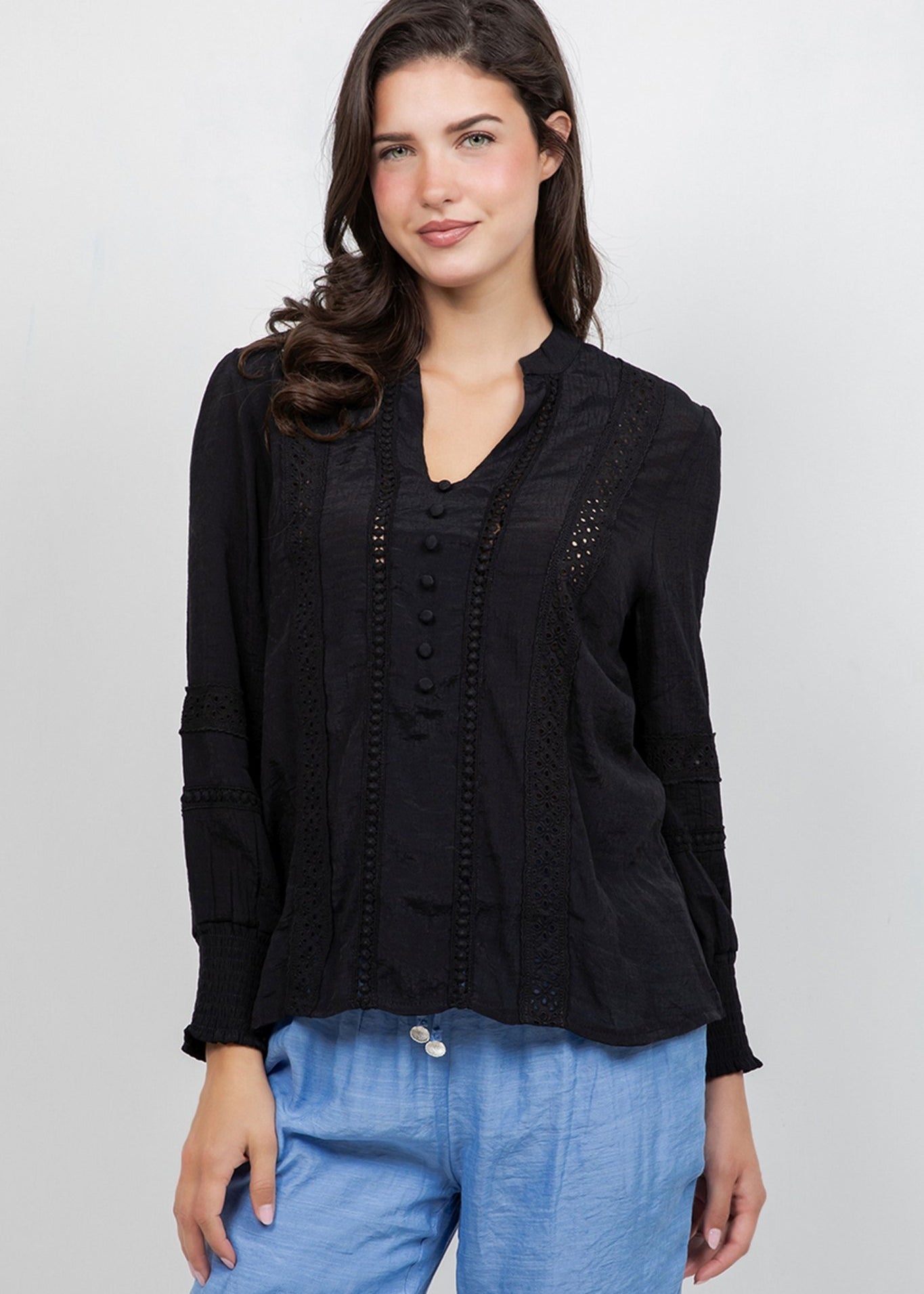 A model wears the Ladies Boho Lace Panel Long Sleeve Blouse in black with lace detailing.