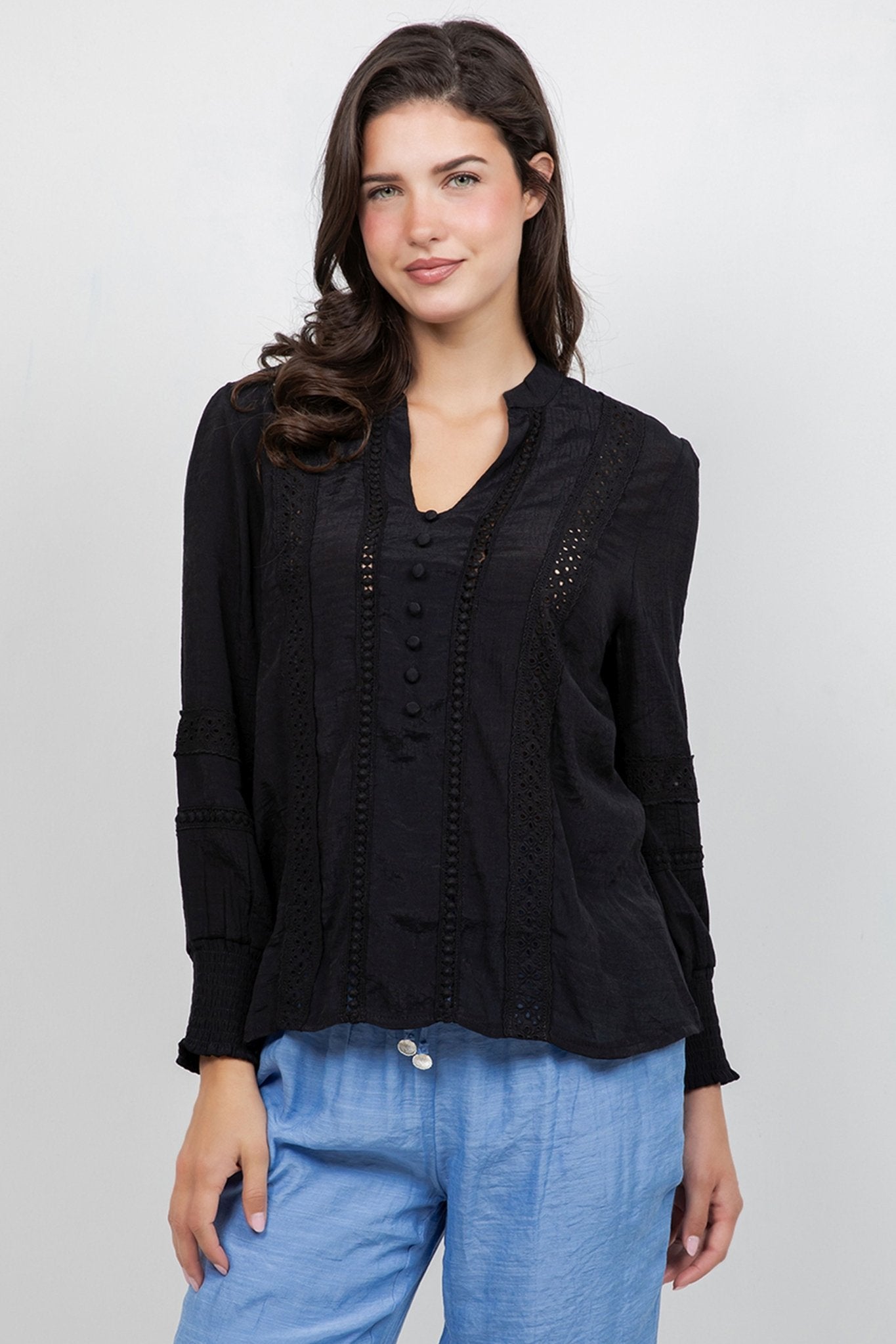 A model wears the Ladies Boho Lace Panel Long Sleeve Blouse in black with lace detailing.