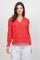 Front view of a woman wearing a red Ladies Boho Lace Panel Long Sleeve Blouse with eyelet details and white drawstring pants.