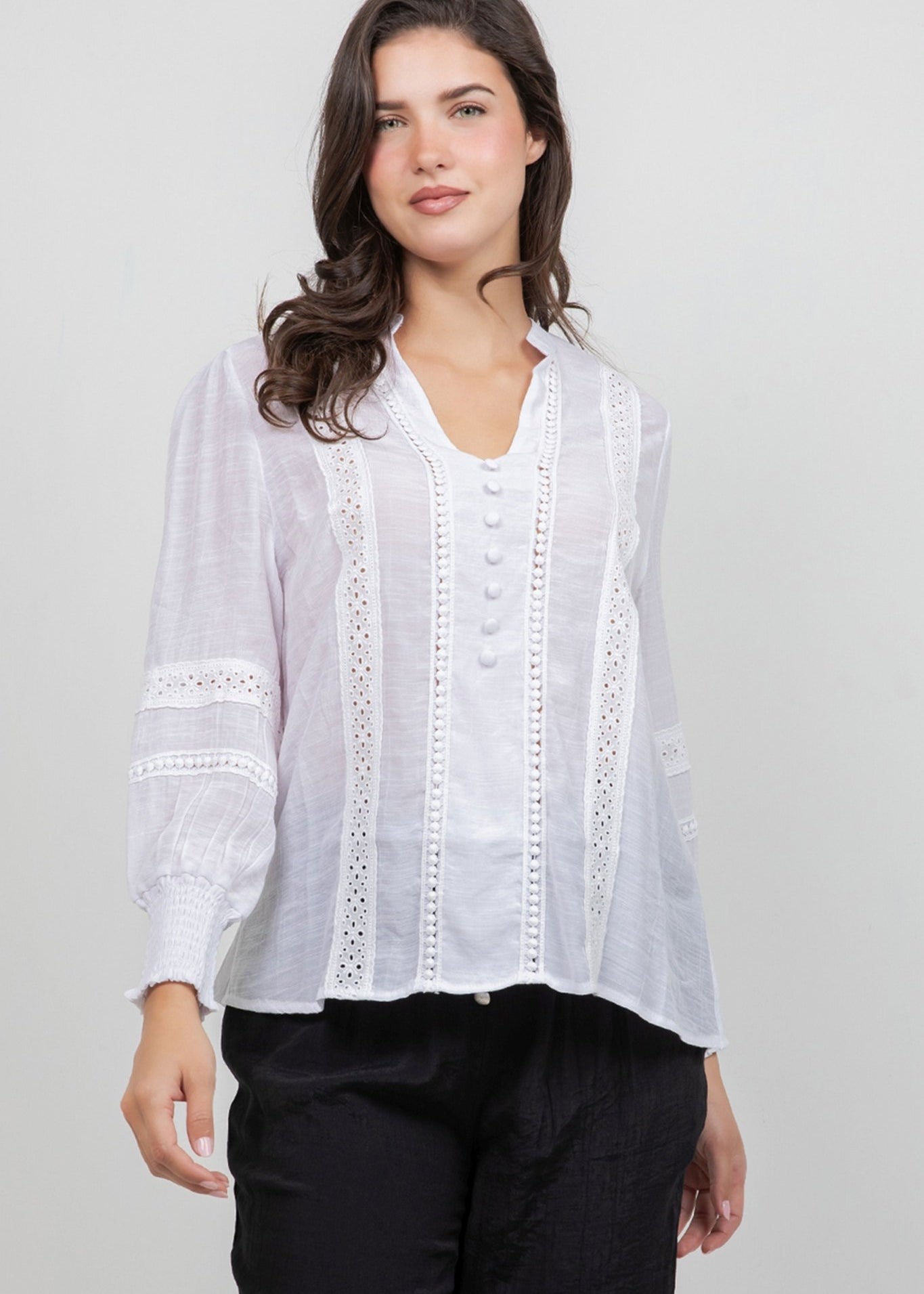 Front view of a woman wearing a white, button-down Ladies Boho Lace Panel Long Sleeve Blouse.