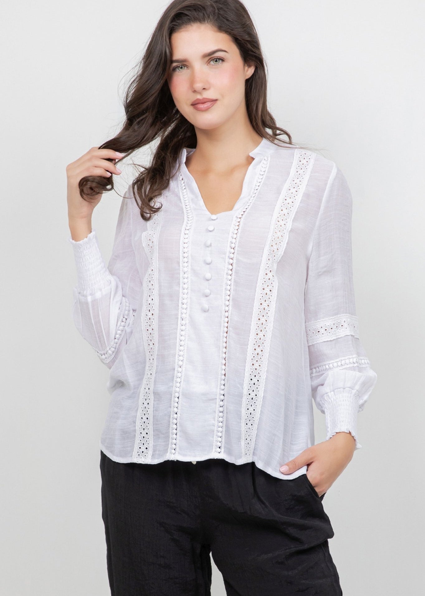 Model wears a white Ladies Boho Lace Panel Long Sleeve Blouse with black trousers.