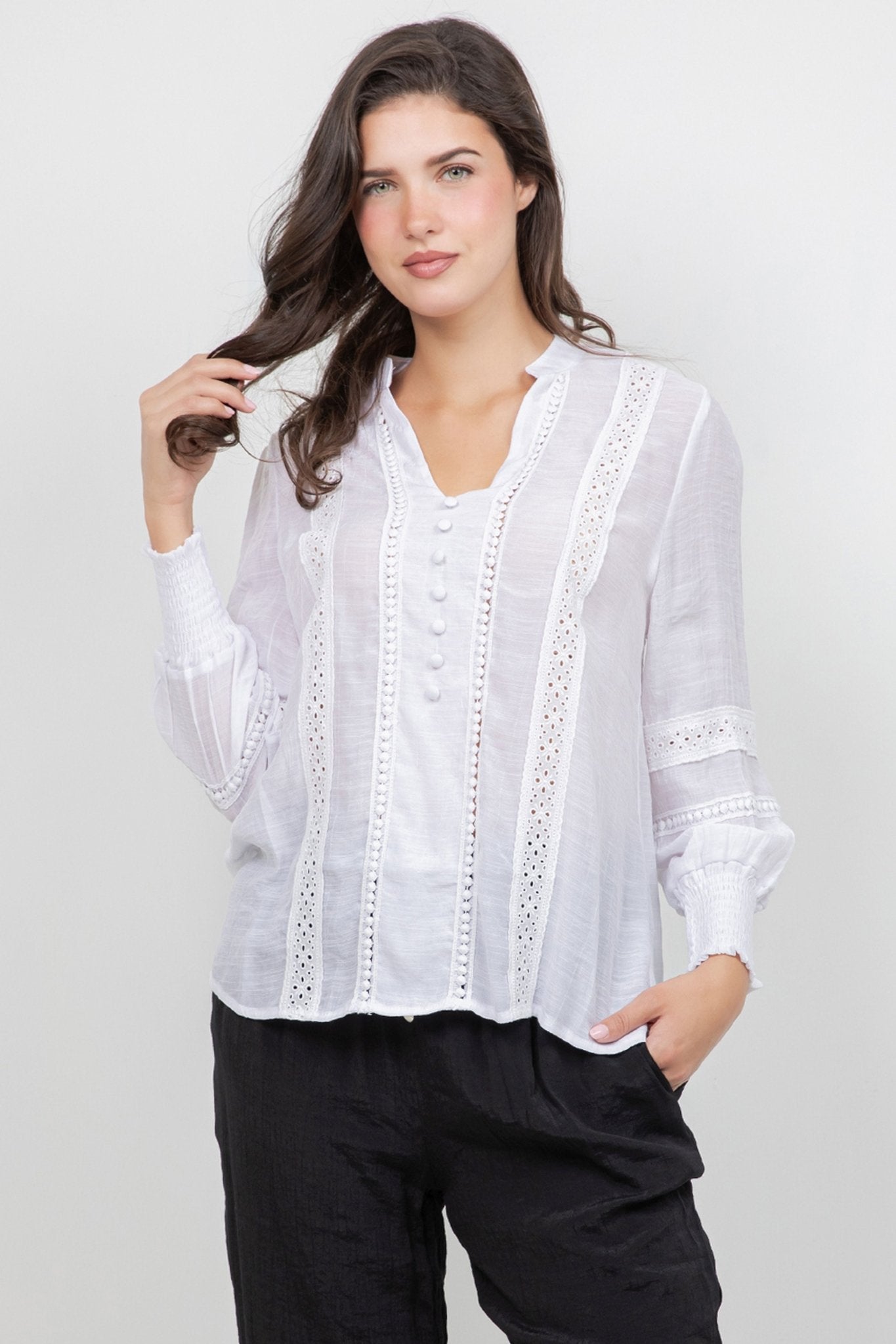 Model wears a white Ladies Boho Lace Panel Long Sleeve Blouse with black trousers.