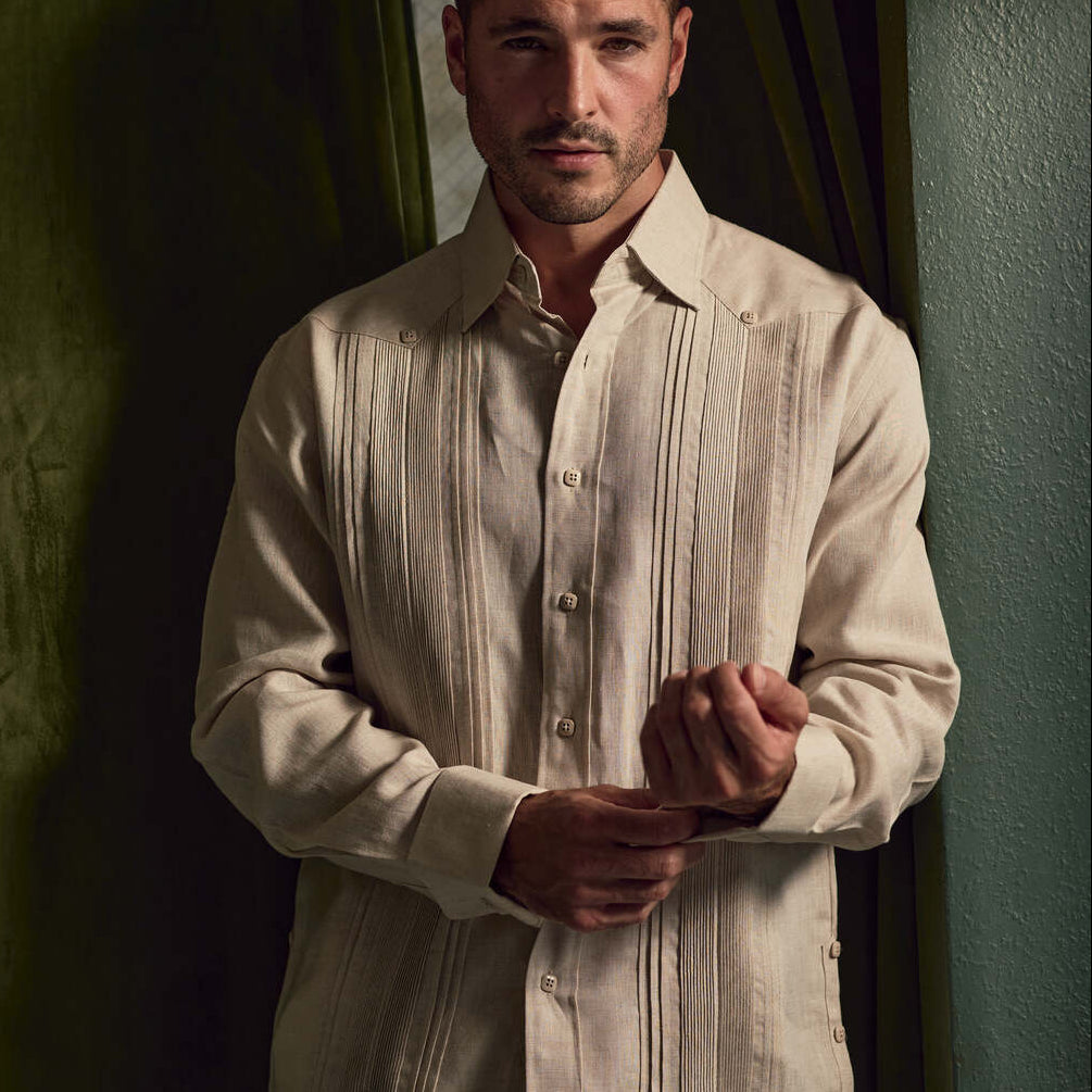 A man adjusting the cuff of a beige Men's Linen Formal Guayabera Long Sleeve Pleated Shirt.