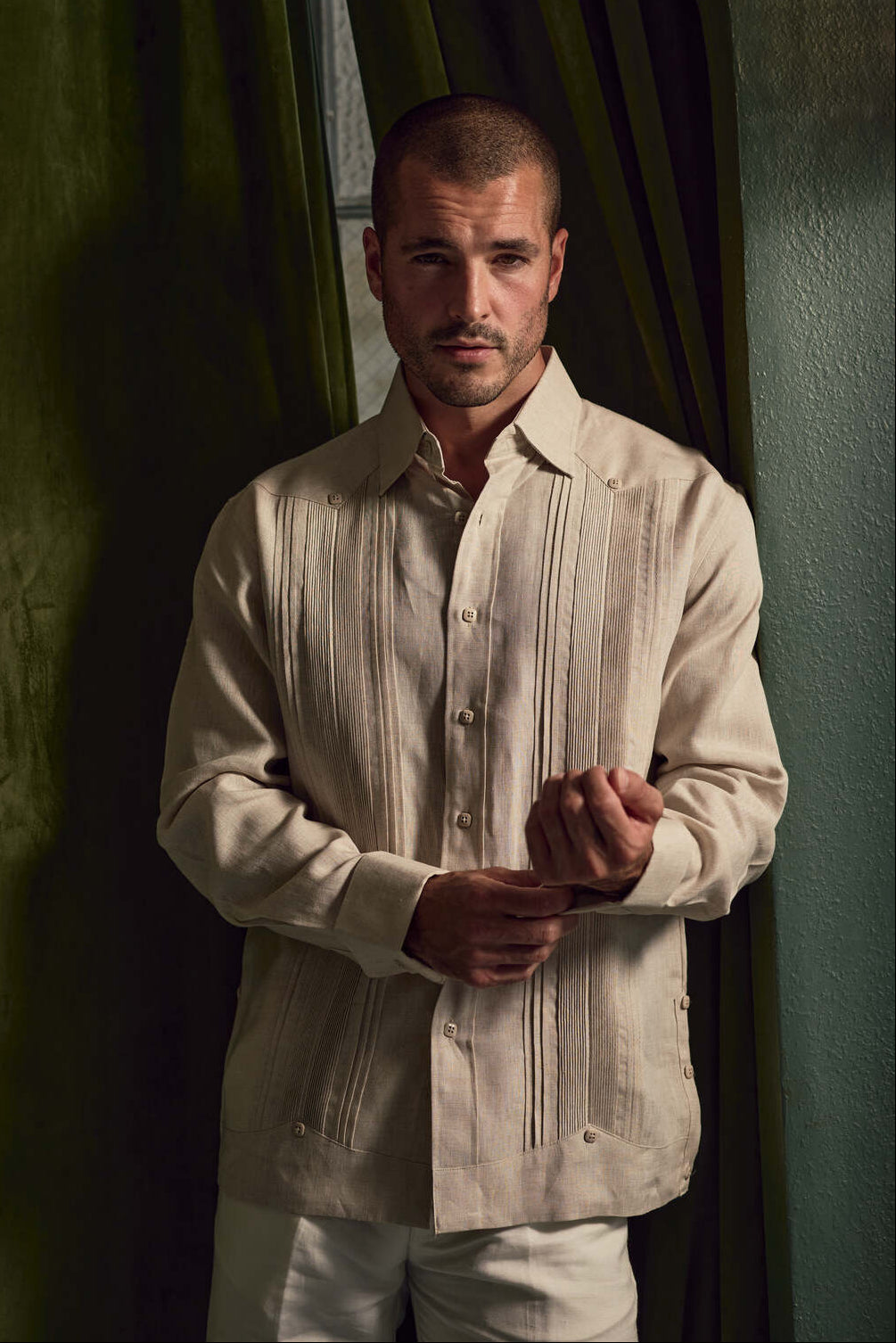 A man adjusting the cuff of a beige Men's Linen Formal Guayabera Long Sleeve Pleated Shirt.
