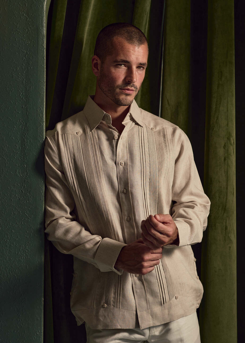 Man models the linen Guayabera shirt, shown in a front view with pleated detail and French cuffs.