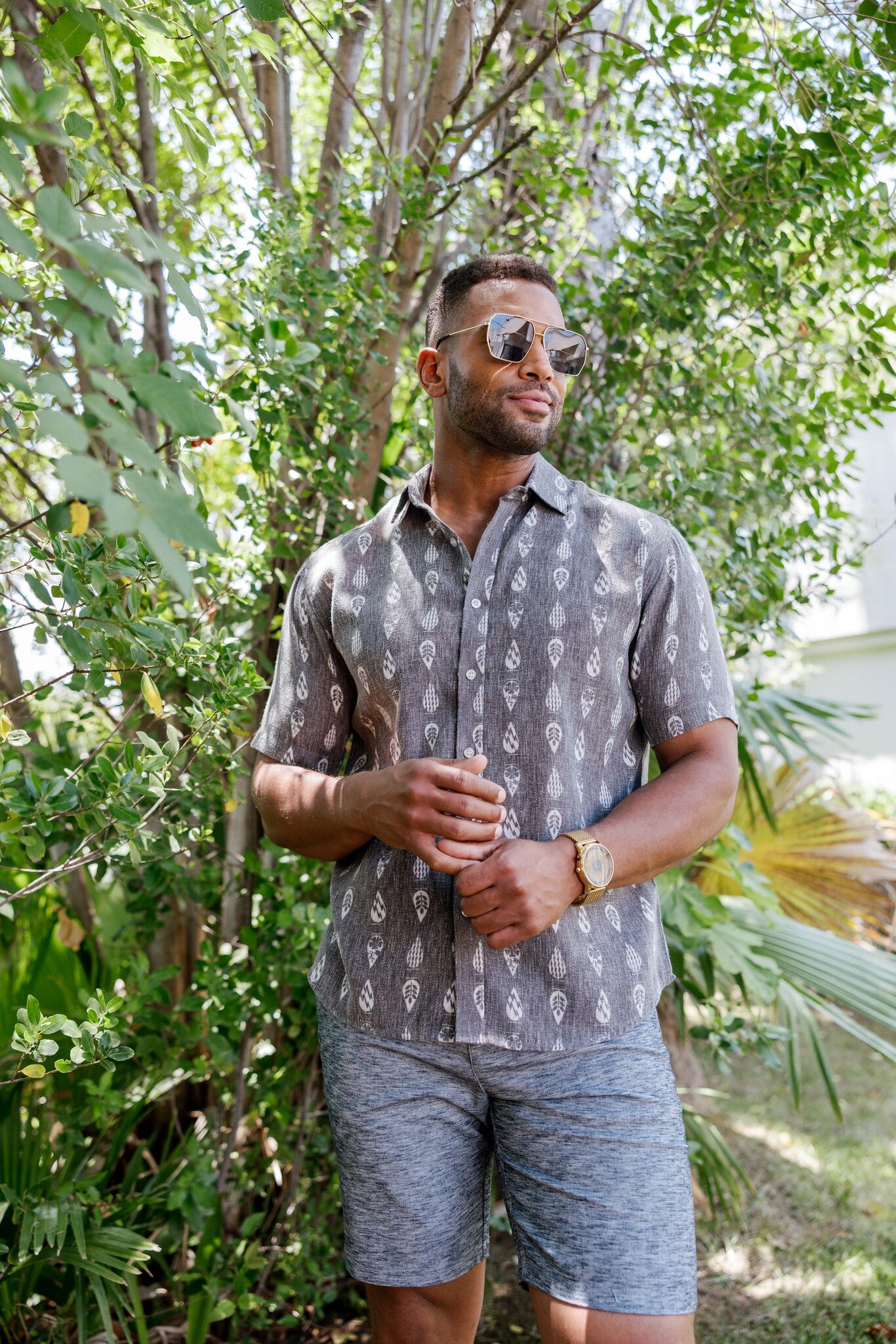Man wears the 100% Cotton Resort Print Short Sleeve Button-Up Shirt, ash gray with a white leaf print.