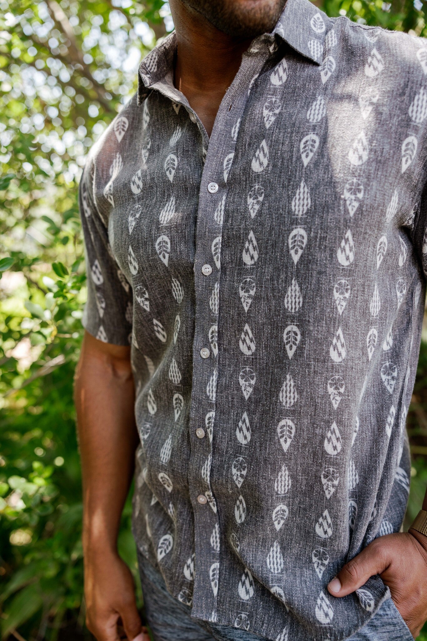 Close-up of a person wearing the Menâ€™s 100% Cotton Resort Print Short Sleeve Button-Up Shirt, featuring a leaf pattern.