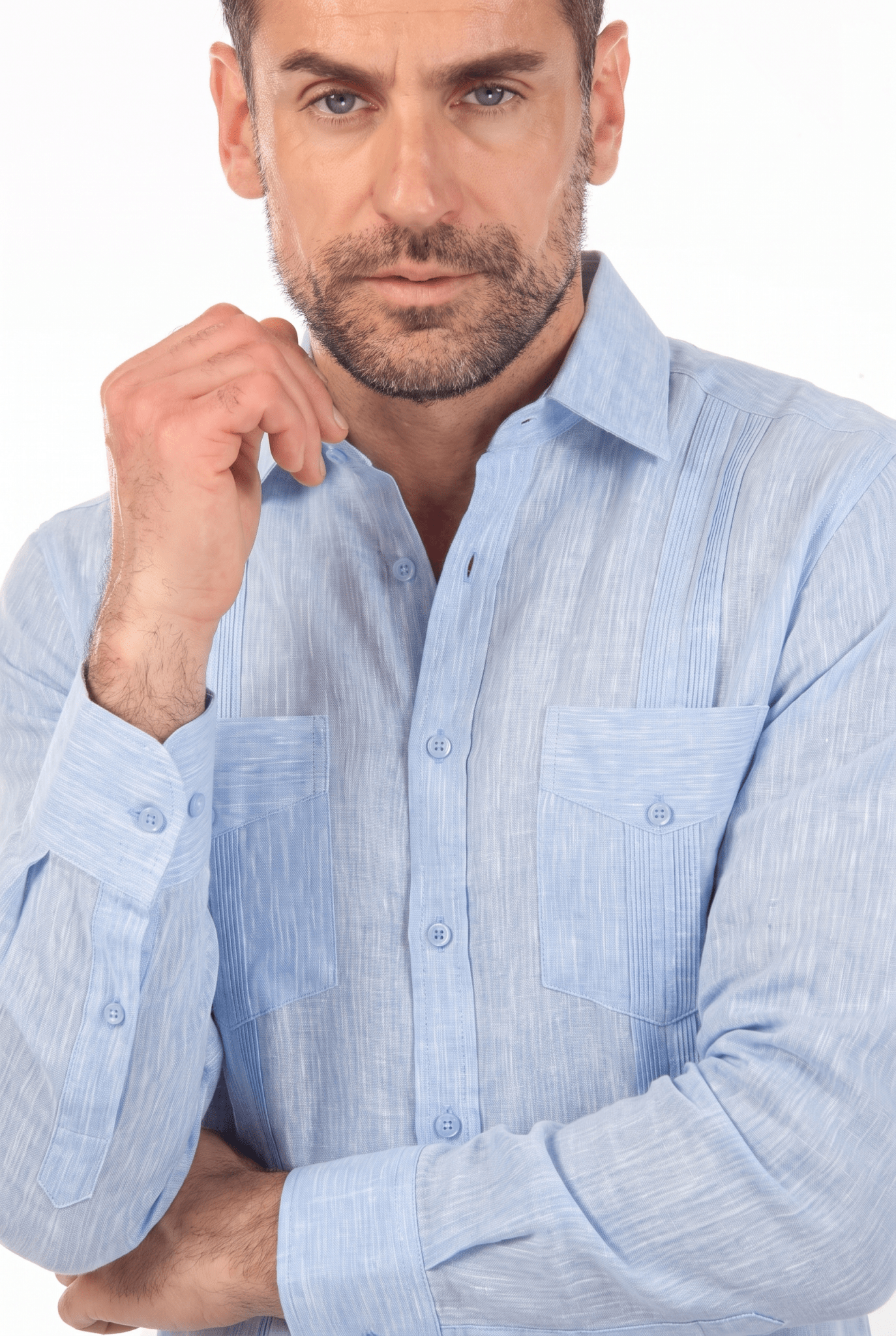 Close-up of a man wearing a light blue, buttoned, long-sleeve Irish Linen Four Pocket Guayabera Shirt.