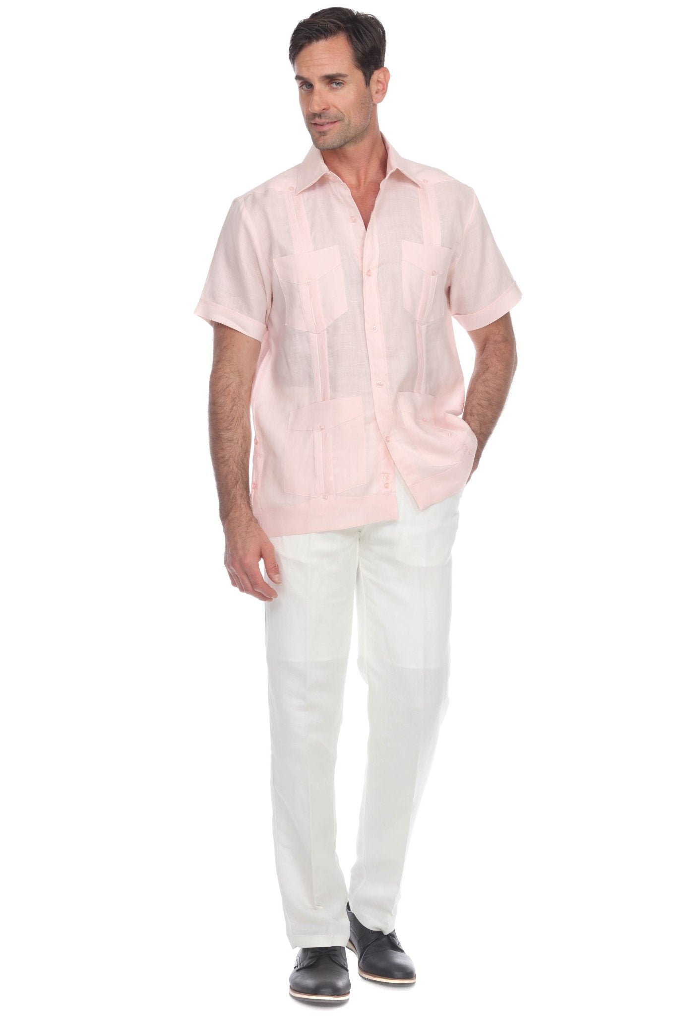 Men’s light pink short sleeve guayabera shirt in premium linen, styled with white trousers for resort wear.