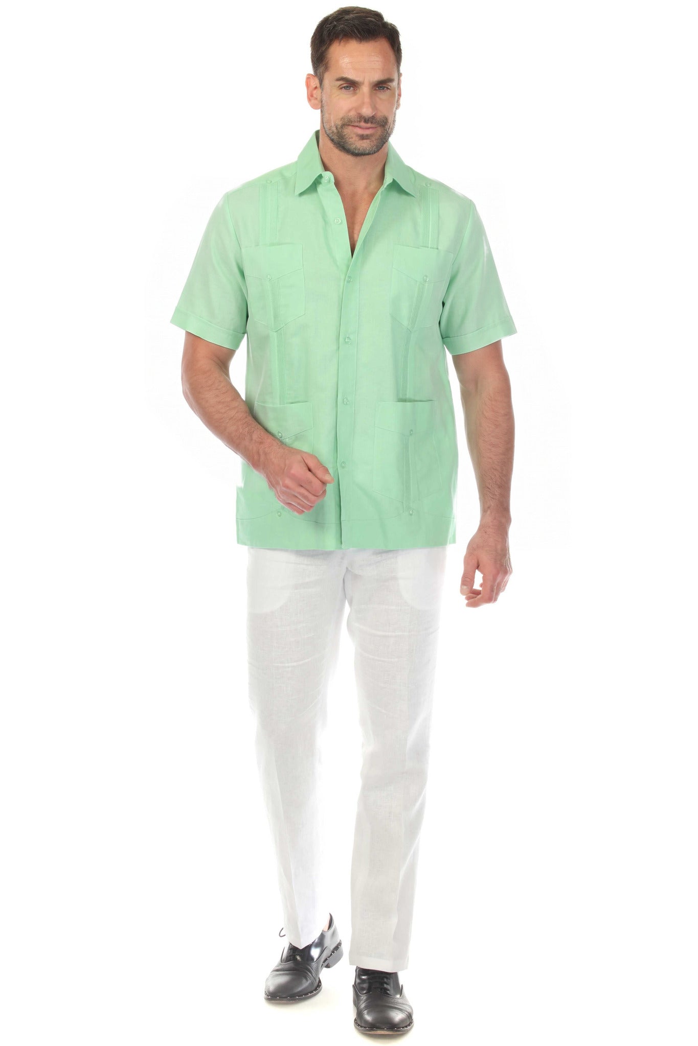 Front view of a men's mint green short sleeve 100% linen guayabera shirt with four pockets and vertical pleats, worn with white linen trousers.