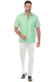 Front view of a men's mint green short sleeve 100% linen guayabera shirt with four pockets and vertical pleats, worn with white linen trousers.