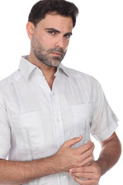 Close-up of the intricate embroidery and four-pocket design on a white short sleeve linen guayabera.