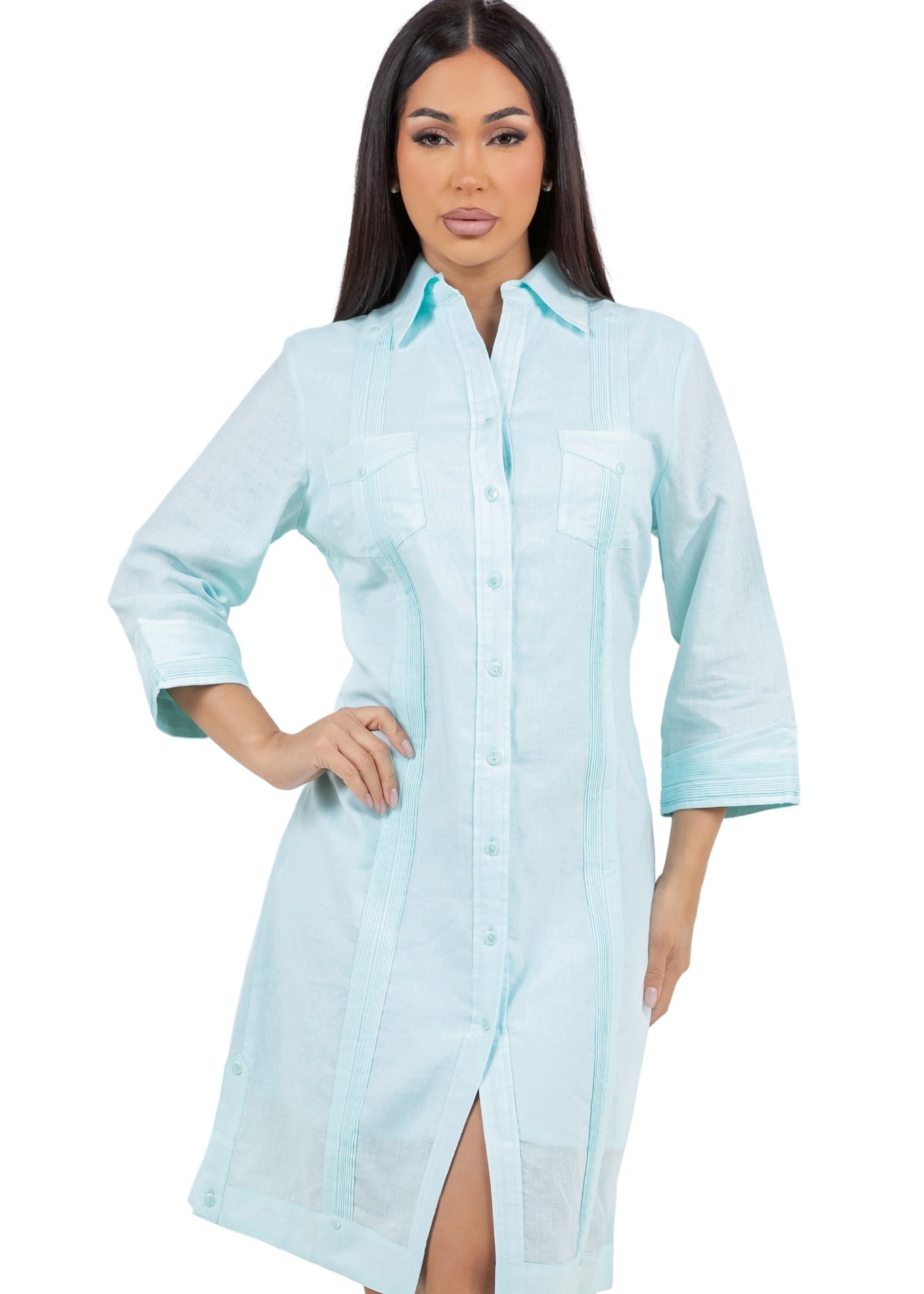 A woman models a light blue, button-down, three-quarter sleeve Women's Guayabera Dress Shirt with pleated details and a thigh-high slit.