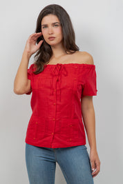 Woman wearing a red off-shoulder top and blue jeans on a gray background