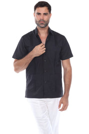 A man wearing a black short sleeve guayabera shirt with white pants, showcasing a sharp and comfortable summer resort style.