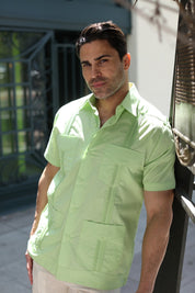 Man wearing a light green short sleeve guayabera shirt, styled as a polished resort-wear essential for sunset dinners.