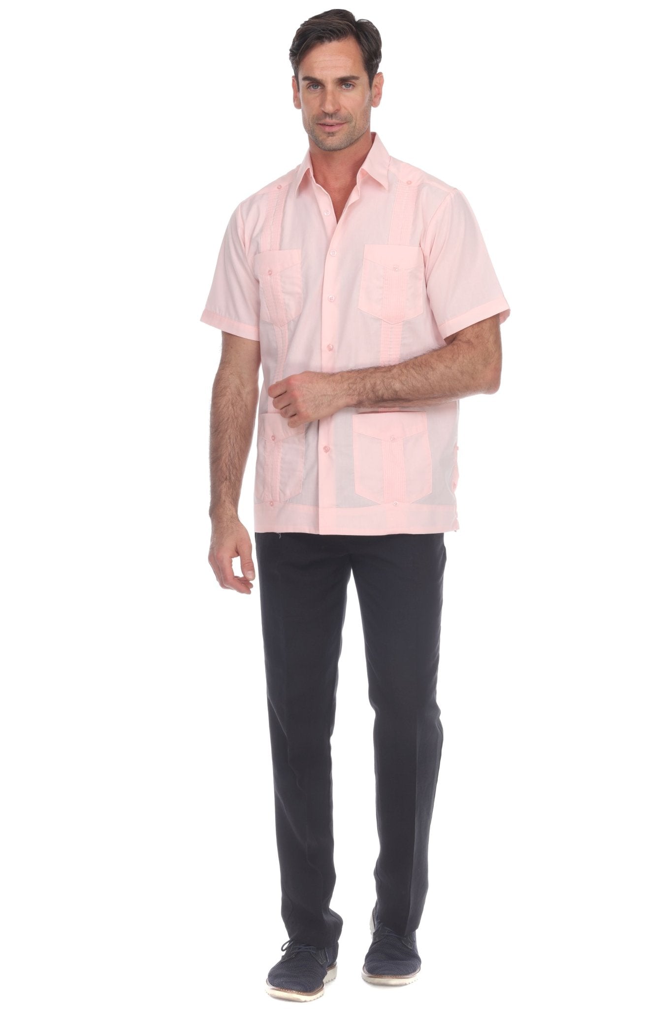 A man modeling a light pink short-sleeve button-up shirt with a subtle tonal pattern, paired with dark trousers and dark sneakers, against a plain white background.